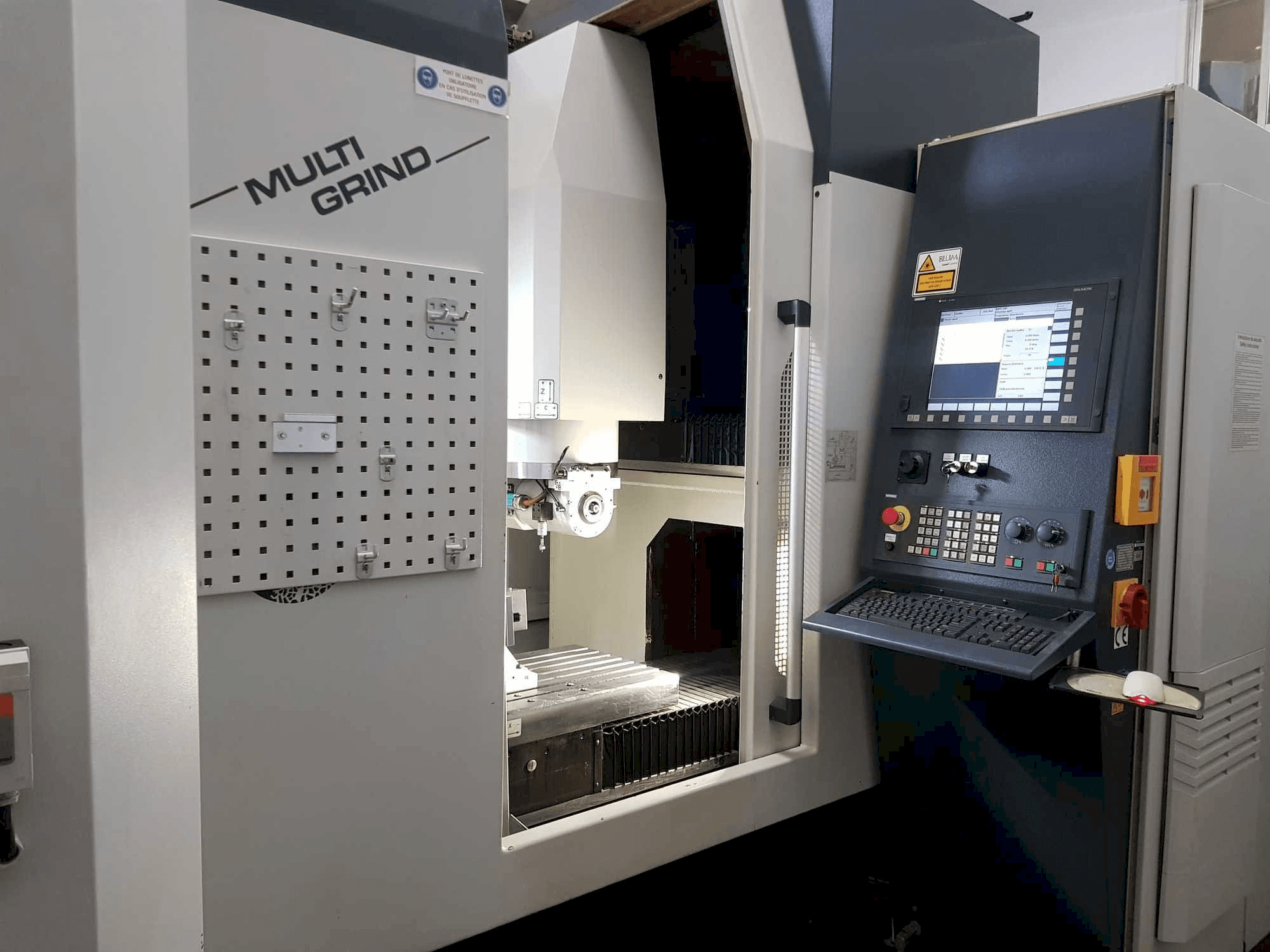 Multi Grind CNC-maskin framifrån, med kontrollpanel, förvaringshylla och ett öppet arbetsområde.